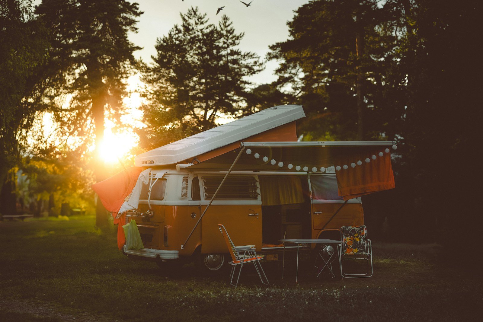 Camper con toldo y comedor exterior al atardecer