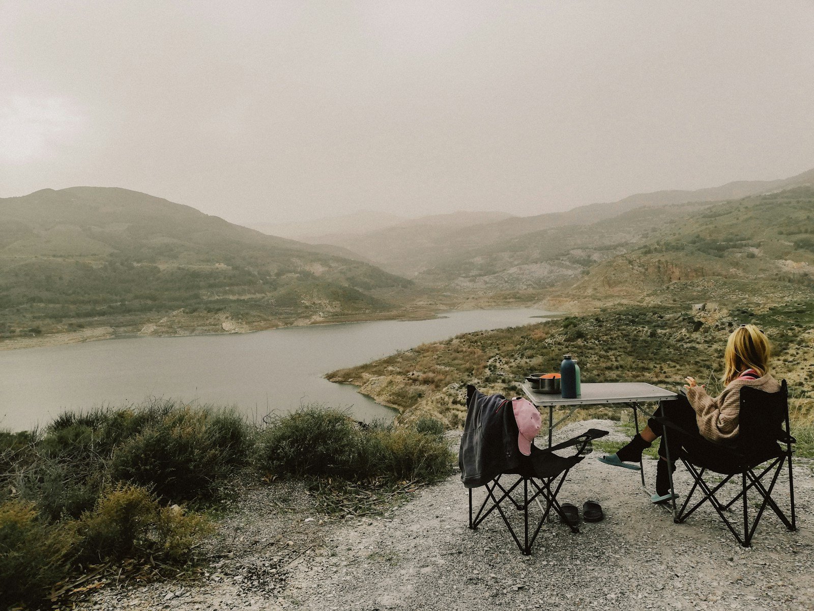 Dos personas sentadas alrededor de una mesa de camping al aire libre
