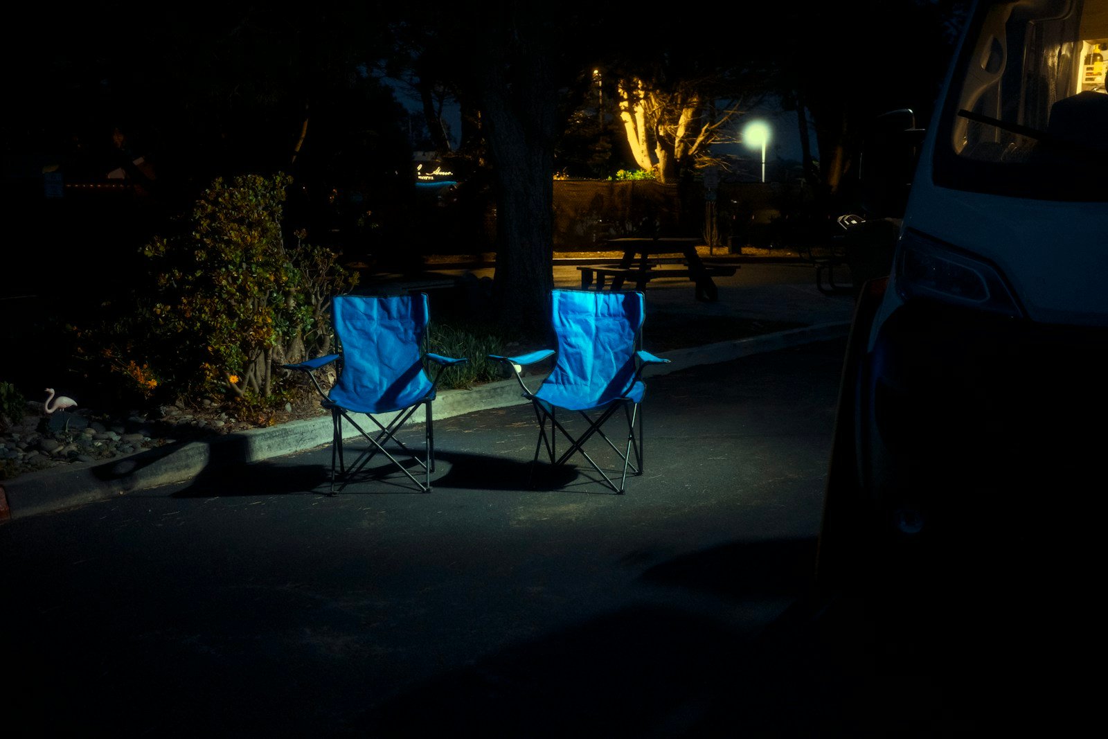 Dos sillas plegables azules junto a una camper por la noche