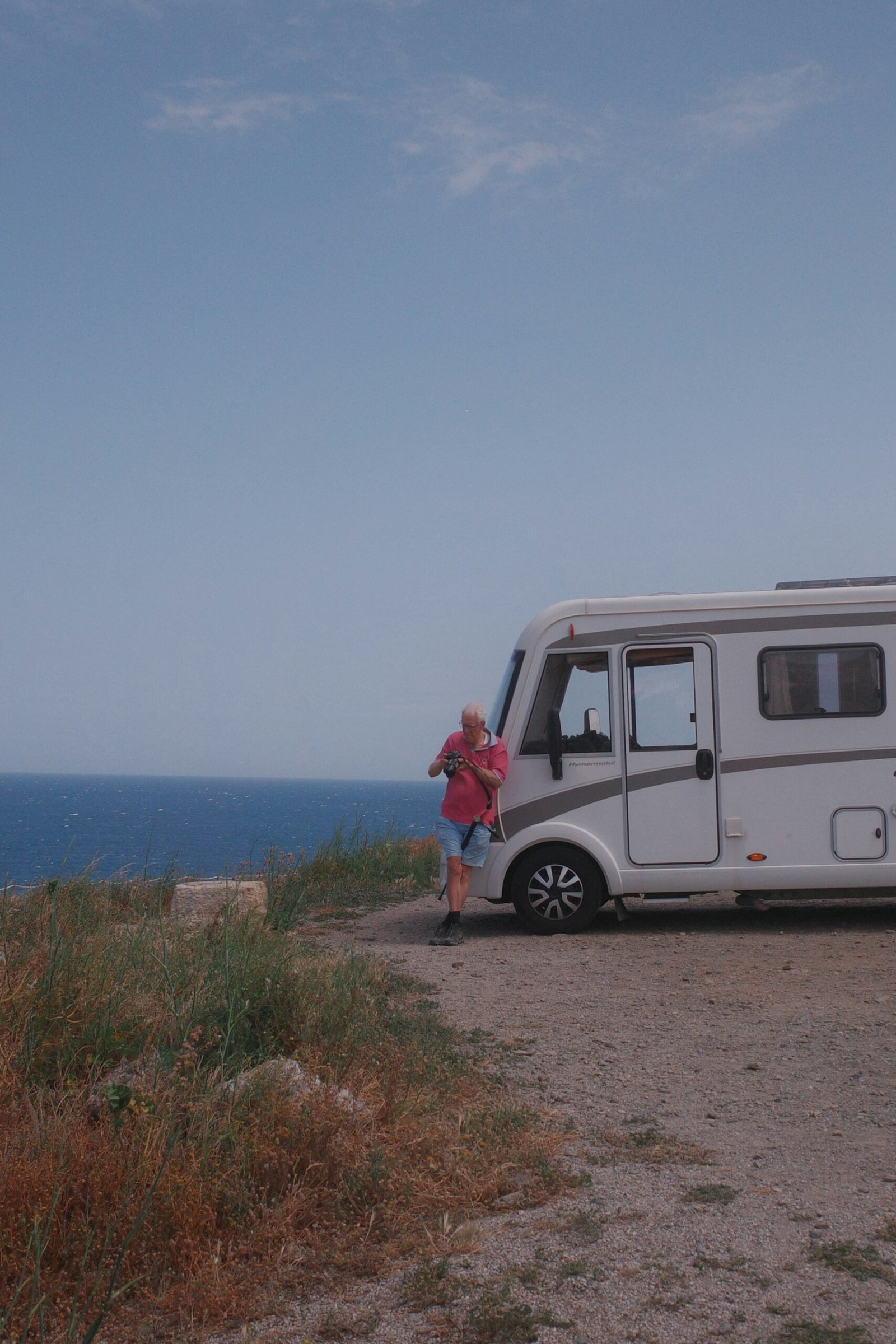 Autocaravana estacionada junto a un acantilado con el mar al fondo