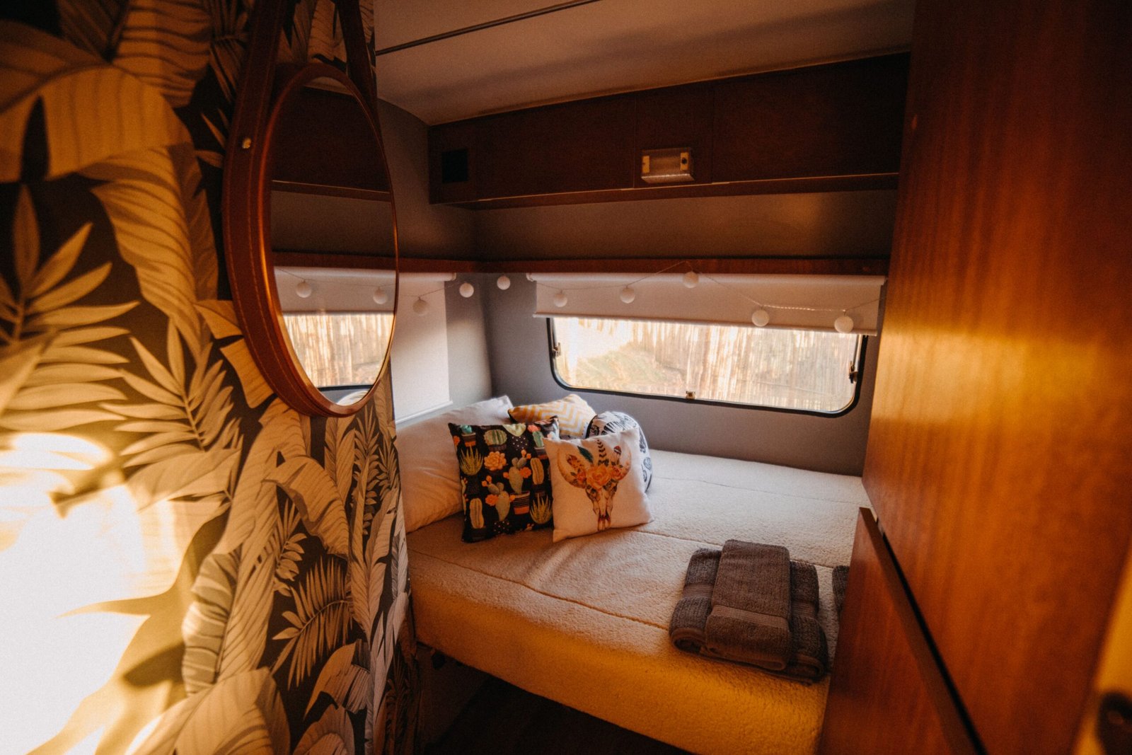 Cama preparada dentro de una camper con iluminación cálida