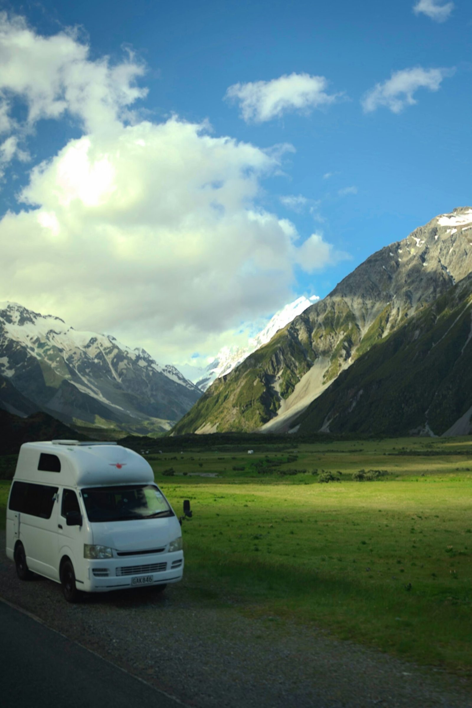 Furgoneta camper blanca en un valle verde rodeado de montañas