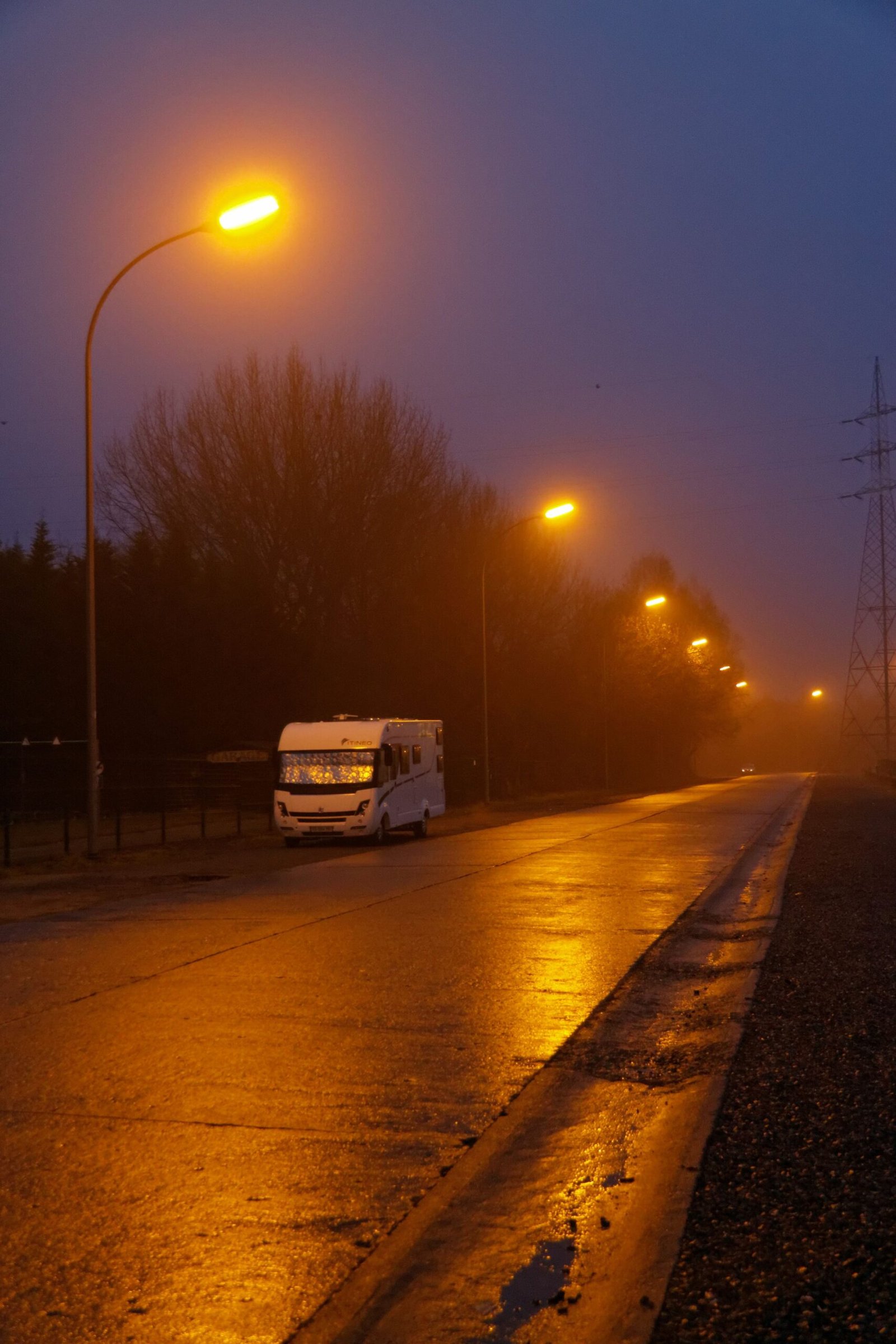 Caravana estacionada junto a una carretera iluminada al anochecer