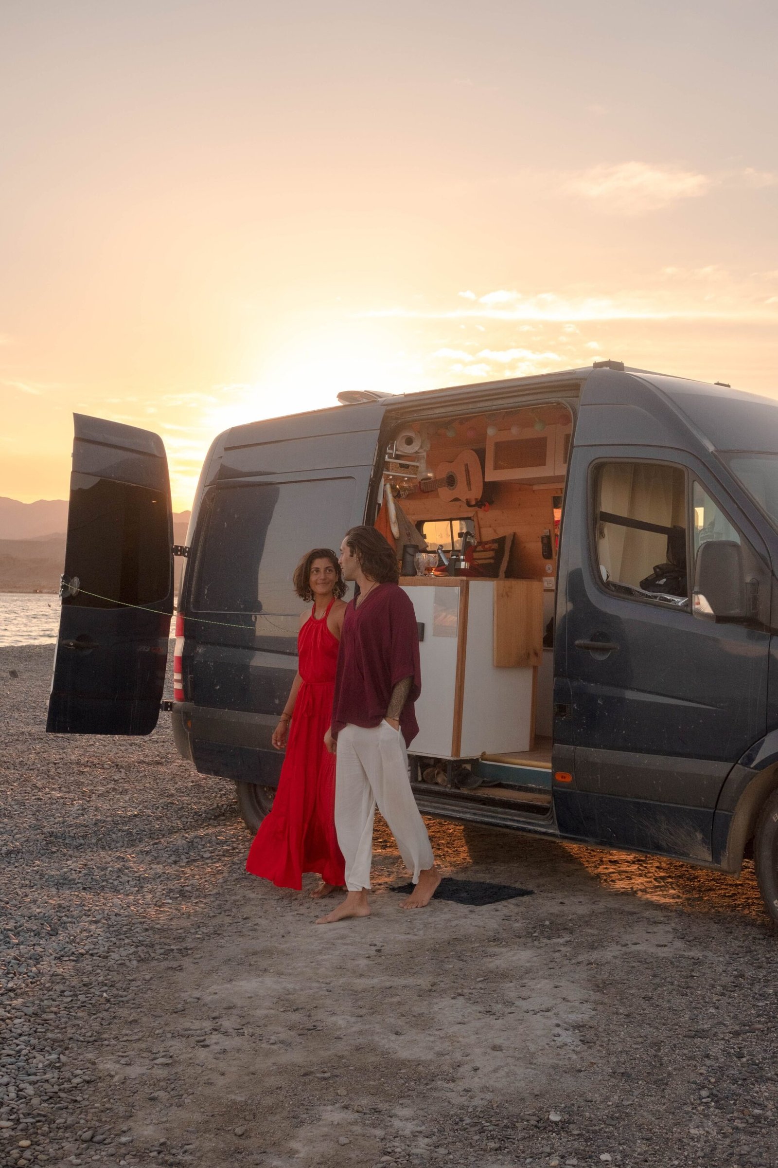 Pareja junto a una camper abierta durante un viaje