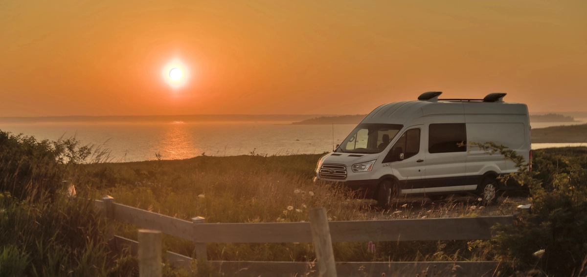 Ford Transit camper en la costa durante el atardecer