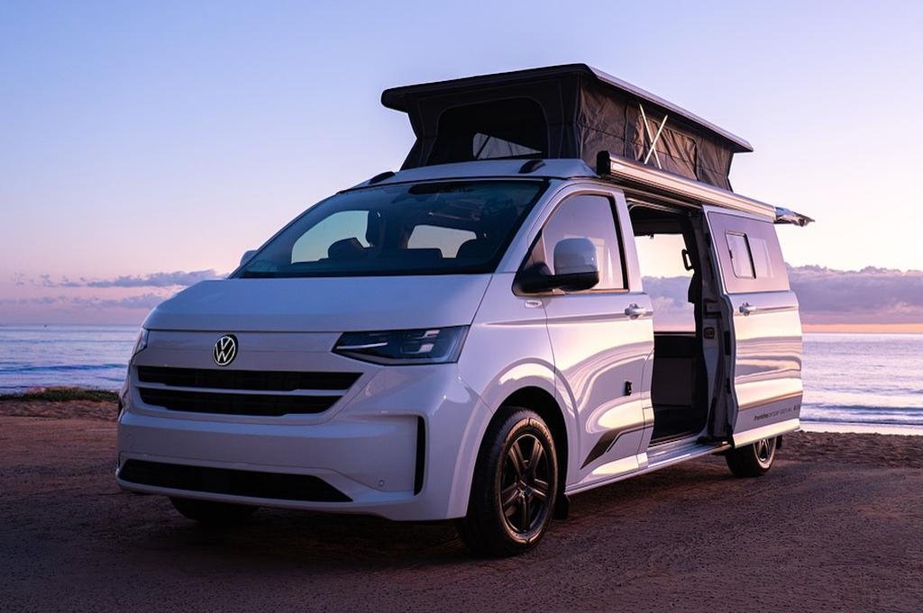 Volkswagen Transporter camper con techo elevable junto al mar al atardecer