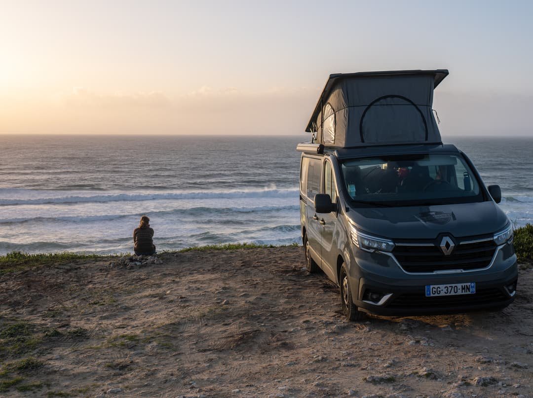 Renault Trafic Hanroad camper con techo elevable frente al océano al atardecer