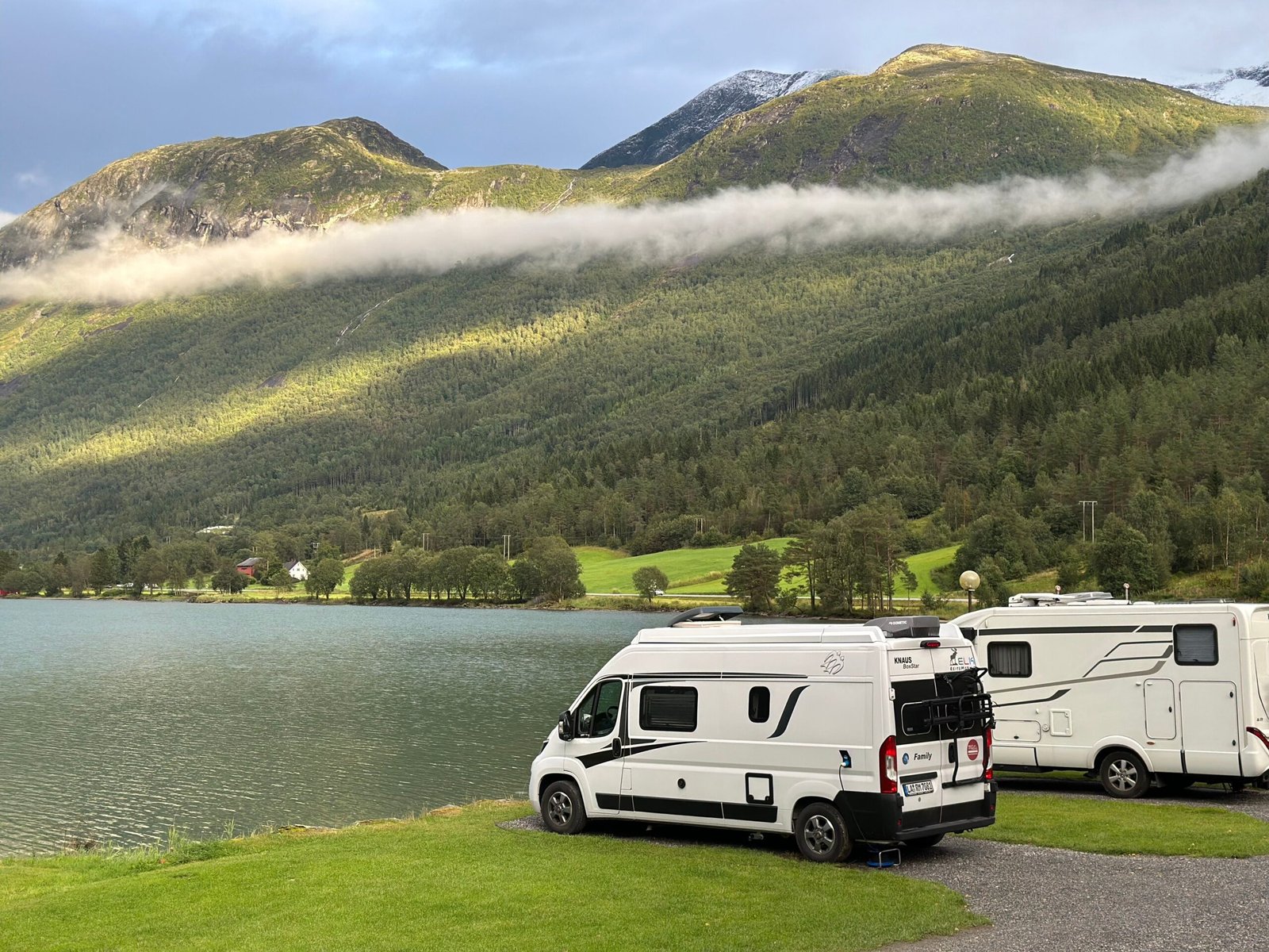 Campers junto a un lago rodeado de montañas en un paisaje de viaje