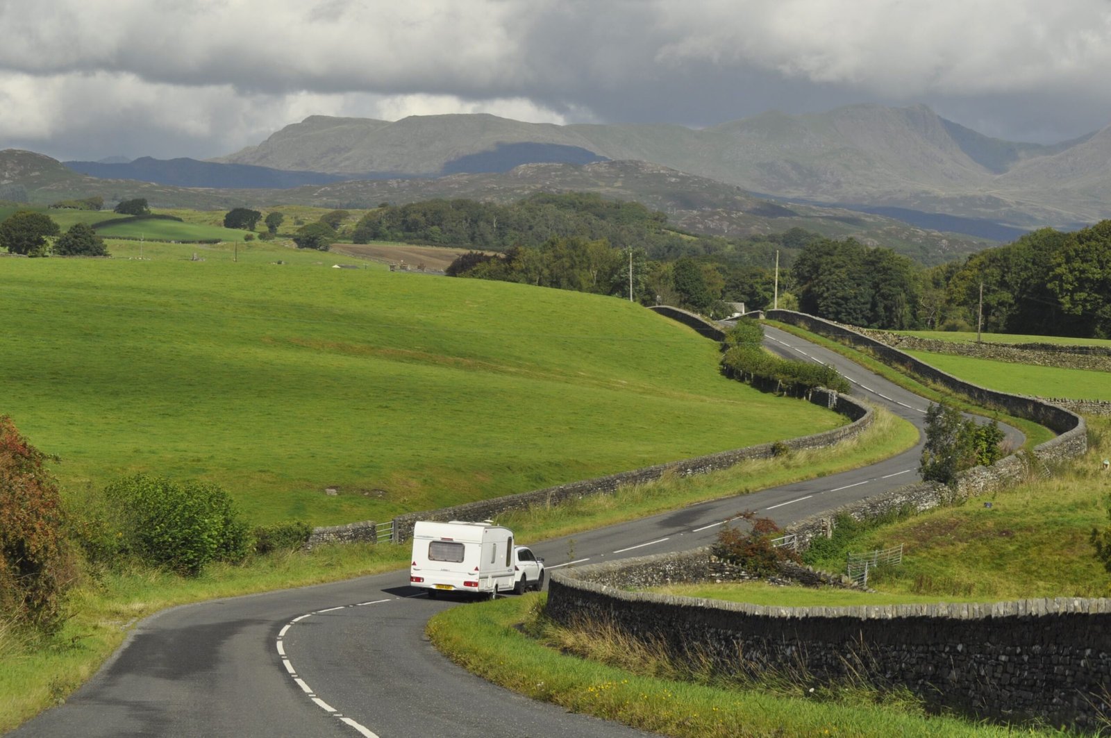 Caravana remolcada por carretera de montaña, imagen ambiental para una guía de compra de caravanas usadas