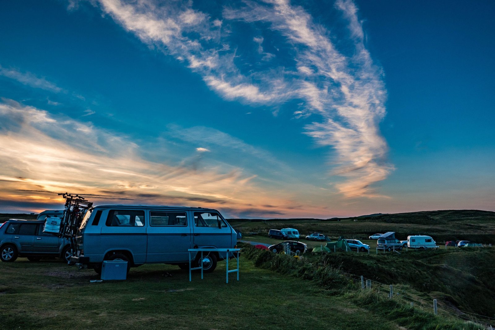 Camping en el campo al atardecer, fotografía ambiental para guía Laika sin representar un modelo concreto