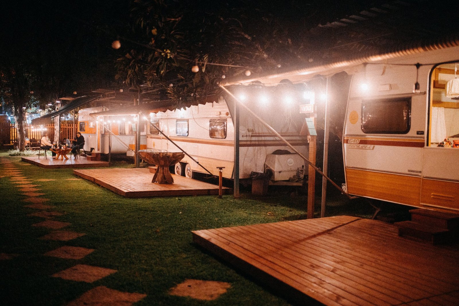 Caravanas ambientadas en un camping iluminado durante la noche, imagen editorial no representativa de un modelo ACE exacto