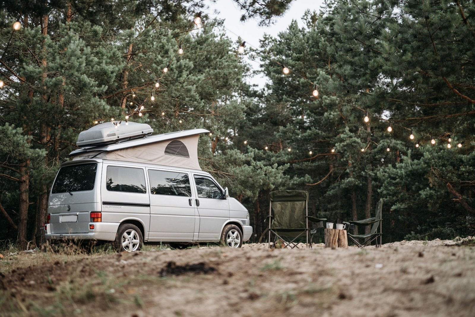 Camper iluminada entre árboles al anochecer; imagen de ambiente, no de la Elnagh Baron 20