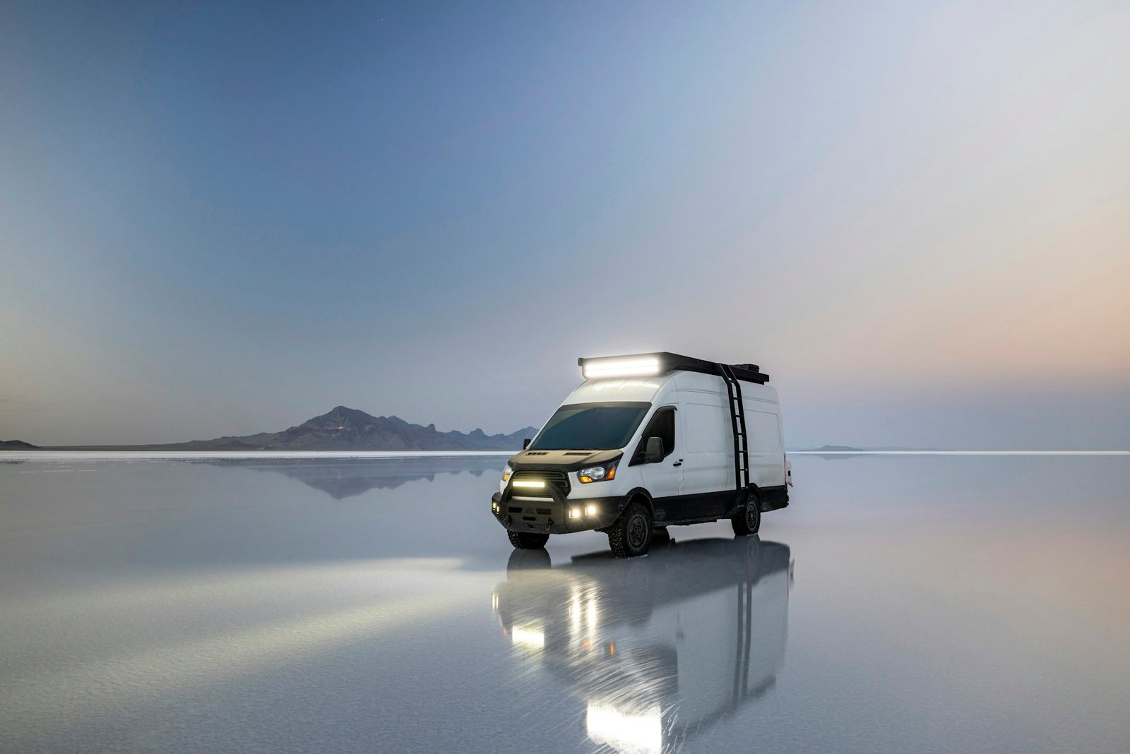 Camper ante un paisaje abierto de salinas al atardecer, fotografía ambiental que no representa una Adria de catálogo
