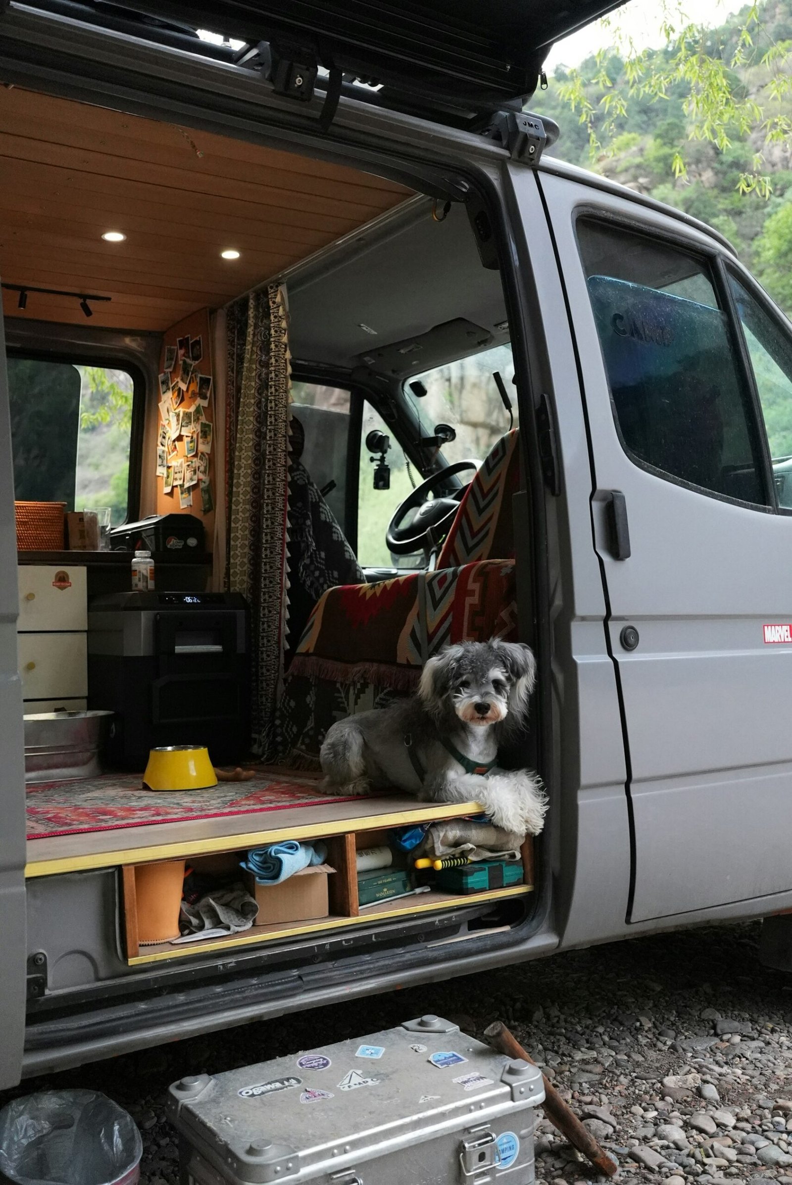 Perro descansando en la entrada de una furgoneta camper durante un viaje