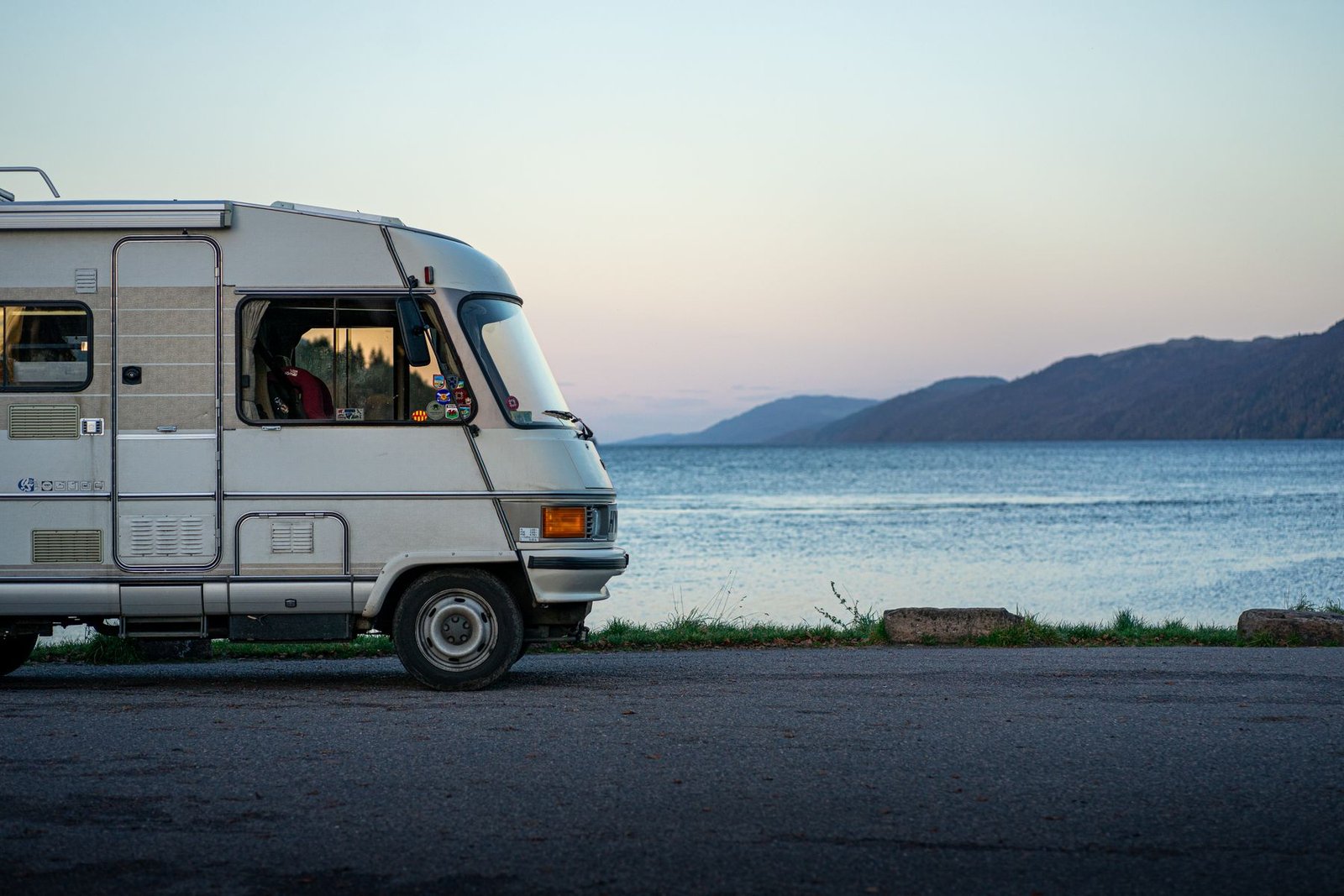 Camper clásica aparcada junto a un lago al atardecer