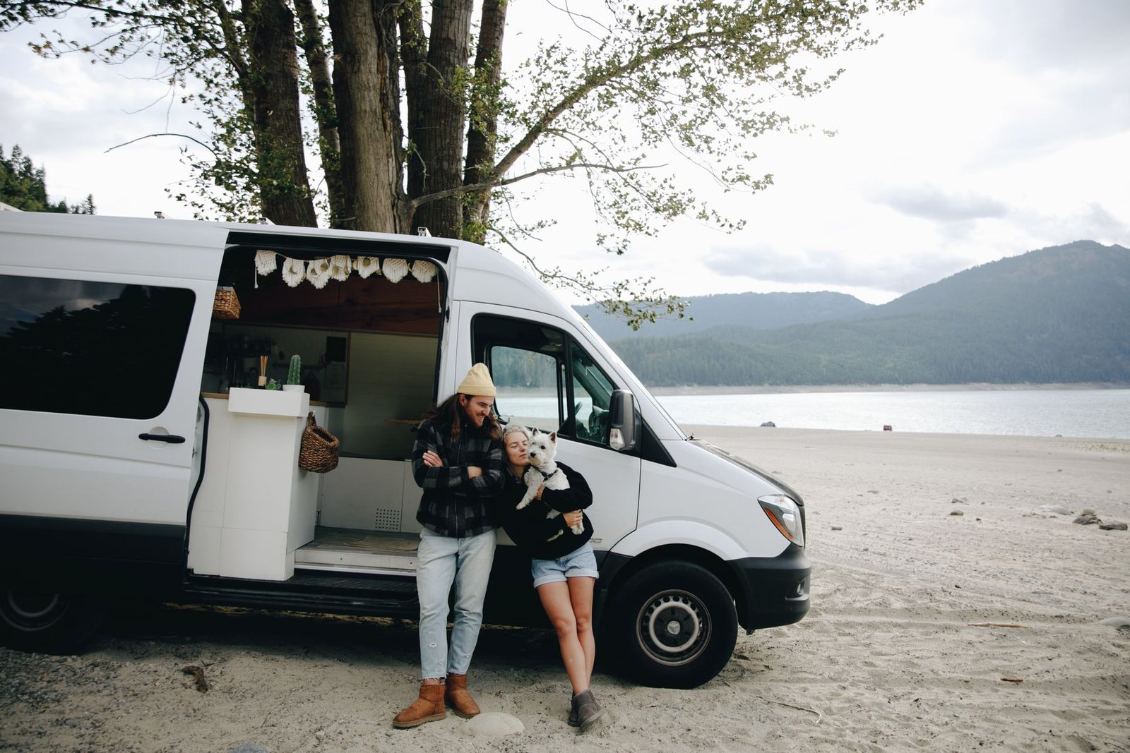 Pareja viajando con su perro junto a un lago y una camper, fotografía editorial que no representa Rimor Kilig 695